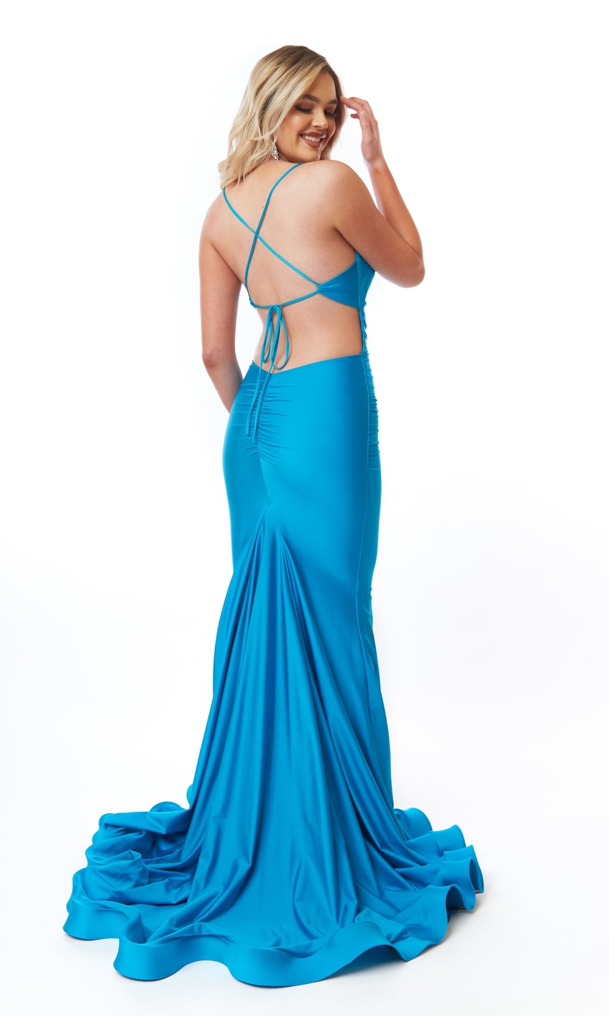 Woman wearing the Tight Long Mermaid Prom Dress: Atria 6700H in bright blue, a floor-length, backless gown with crisscross straps, standing and looking over her shoulder against a white background.